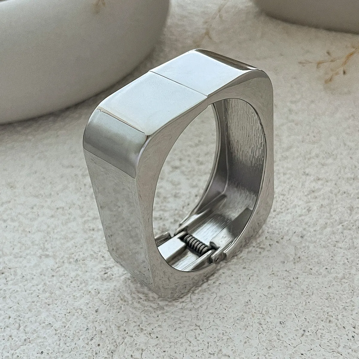 Metal texture glossy spring bracelet with geometric square mirror design in gold colour on white background