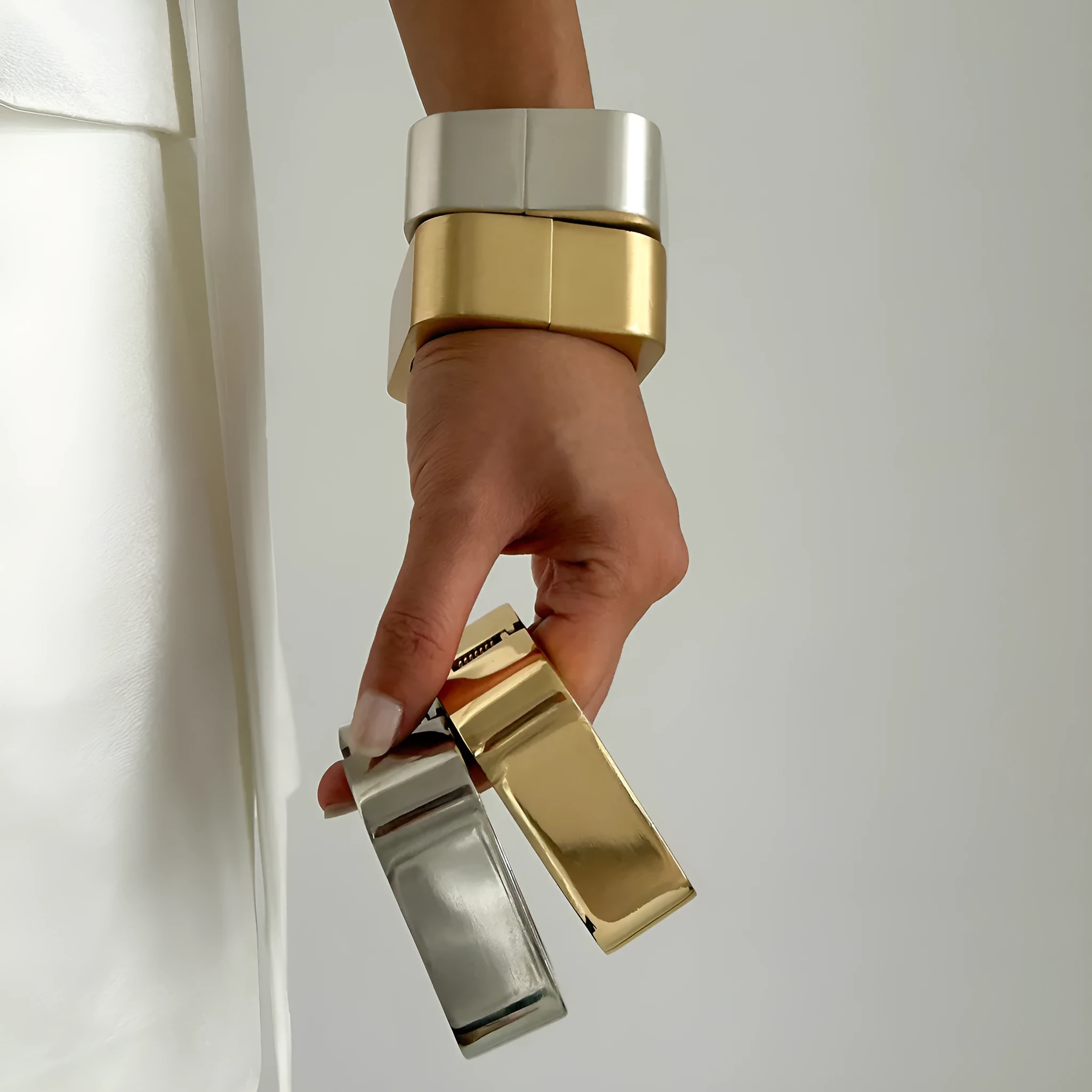 Metal texture glossy spring bracelet with geometric square mirror design in gold colour on white background