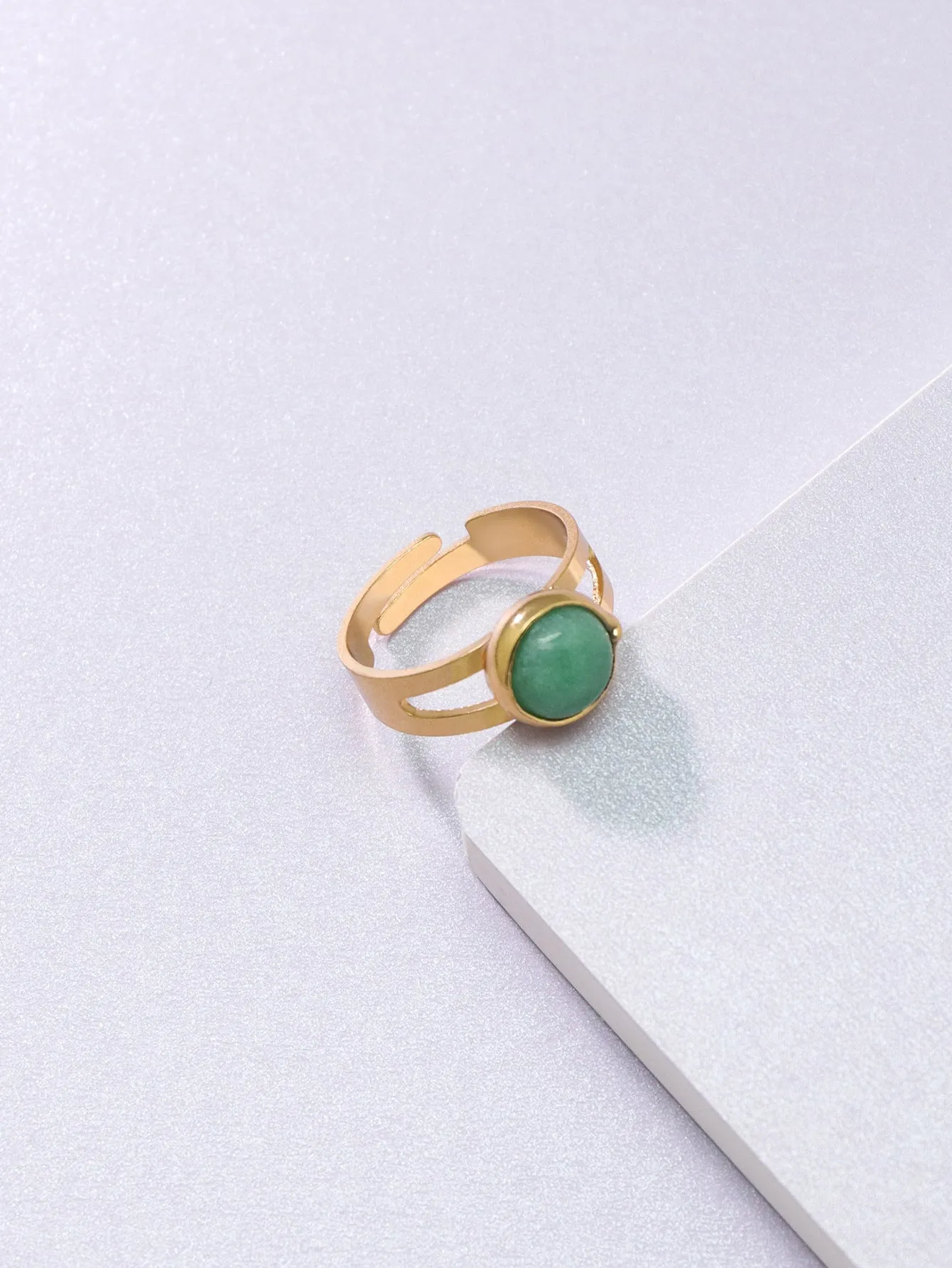 Copper adjustable ring with green natural stone inlay and gold-toned plating on white background