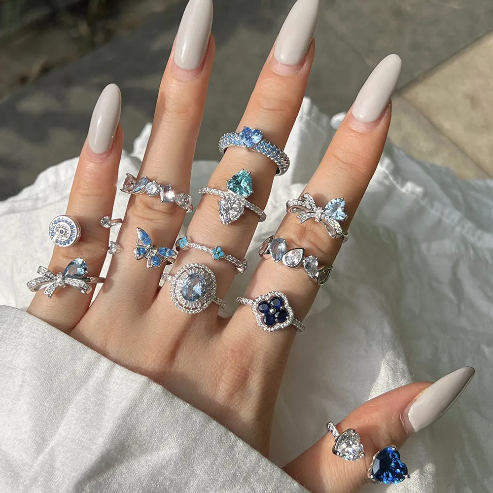 Women's S925 sterling silver ring with sea blue zircon heart or bow shape on plain background