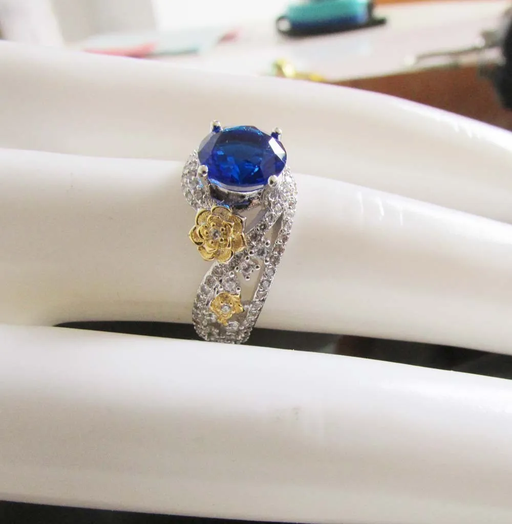 Flower rose two-tone copper ring for women with blue artificial gemstone on a white background
