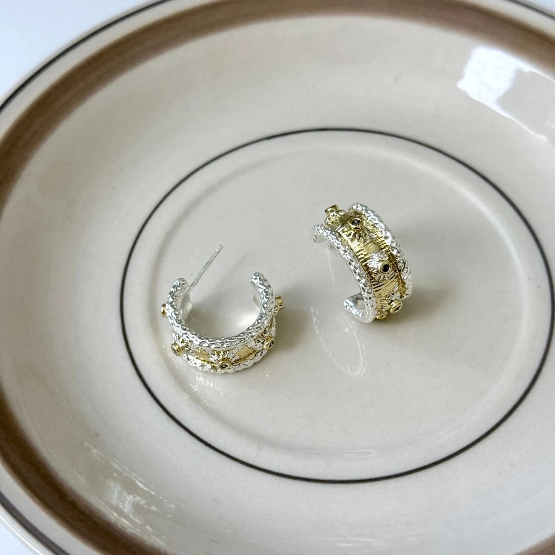 Gold and silver C-shaped brushed ring earrings on display, copper with 925 silver needles