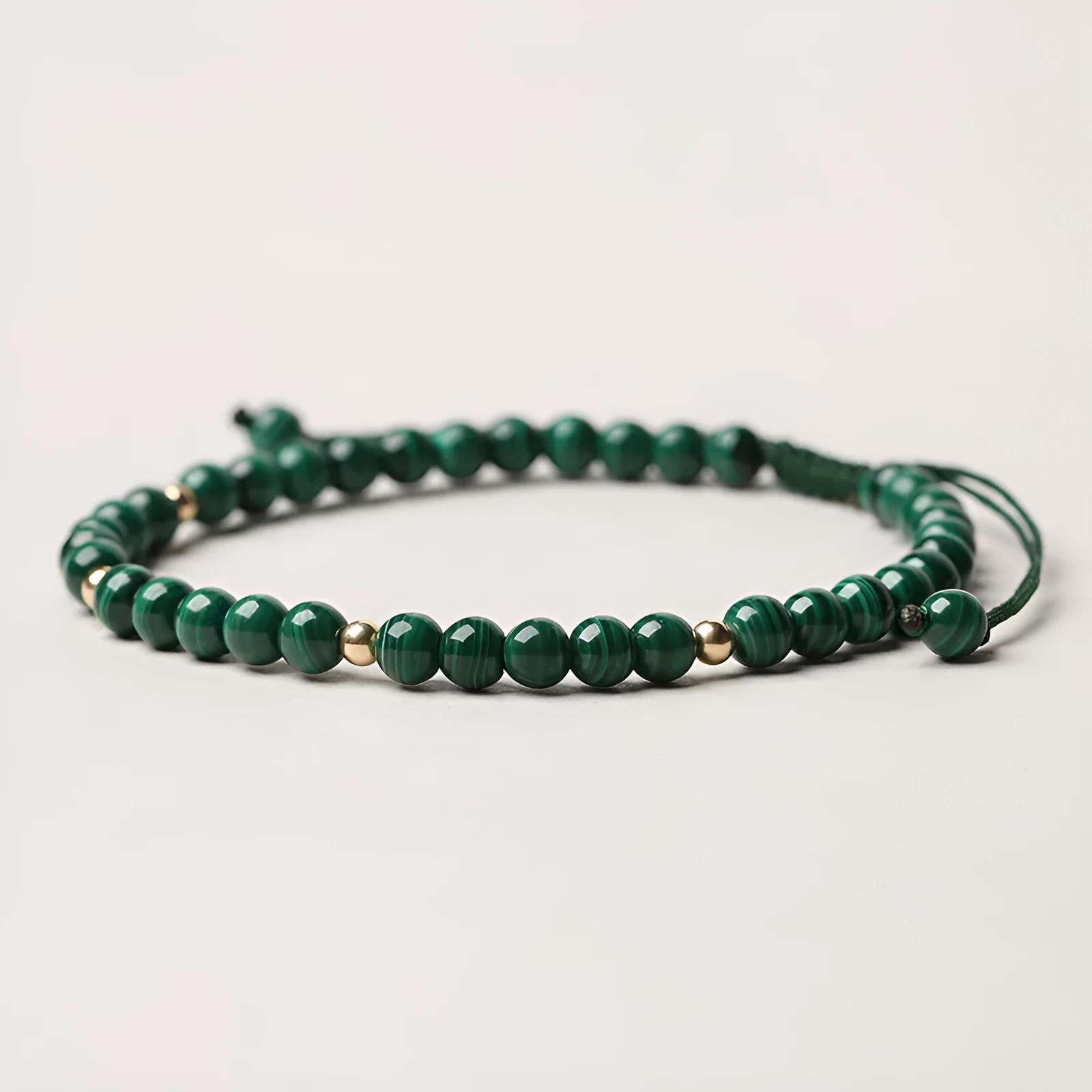 Green malachite stone bracelet with golden beads on woven strap, zodiac animal motif.