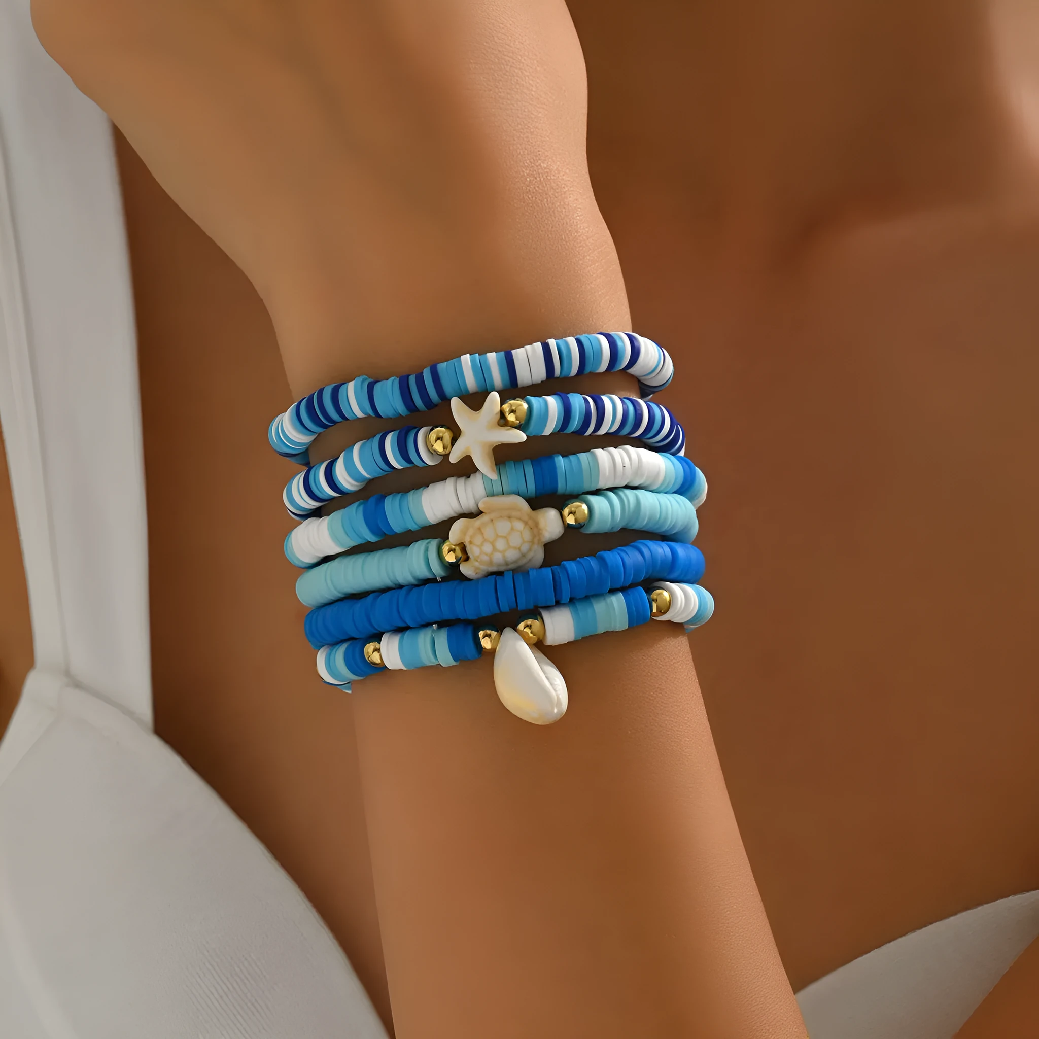 Six handmade Bohemian blue polymer clay bracelets with shell designs and geometric shapes arranged together