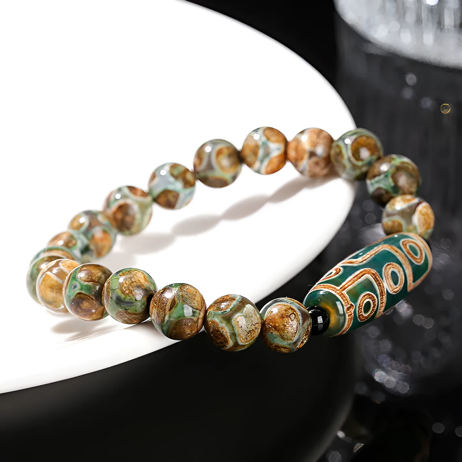 Handmade green dzi bead barrel bracelet with 8mm round geometric beads on a wrist.