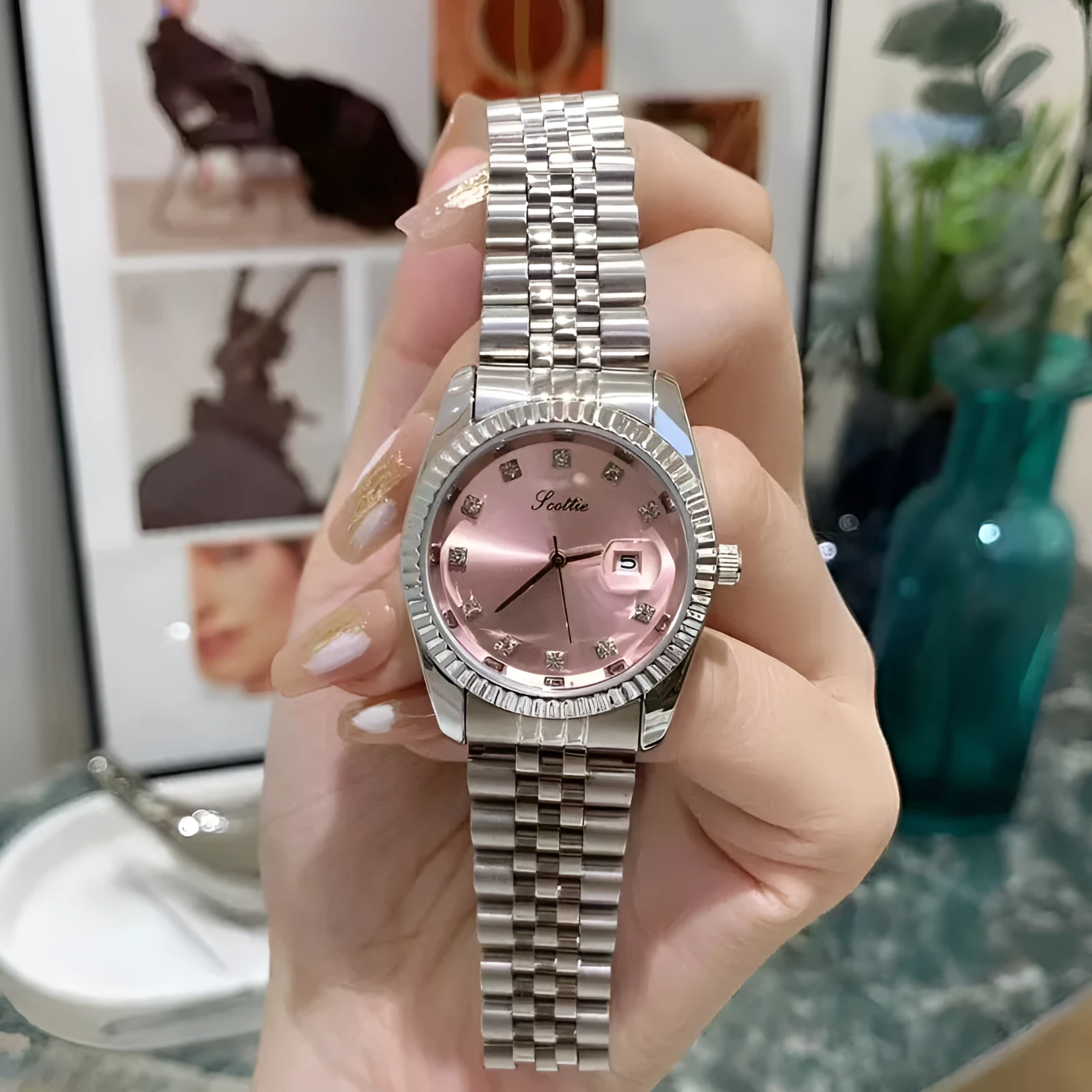 Women's casual analogue calendar watch with gold case, white dial, and steel belt on wrist