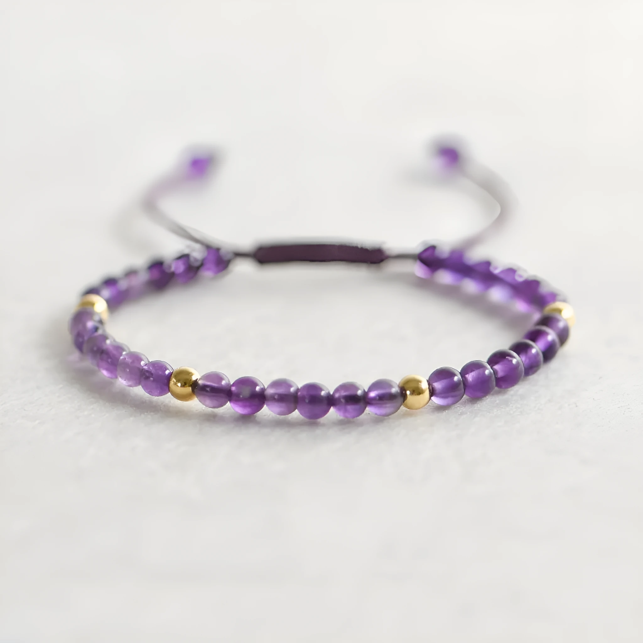 Handmade purple amethyst and 14K gold bracelet with 4mm round beads on a wrist.