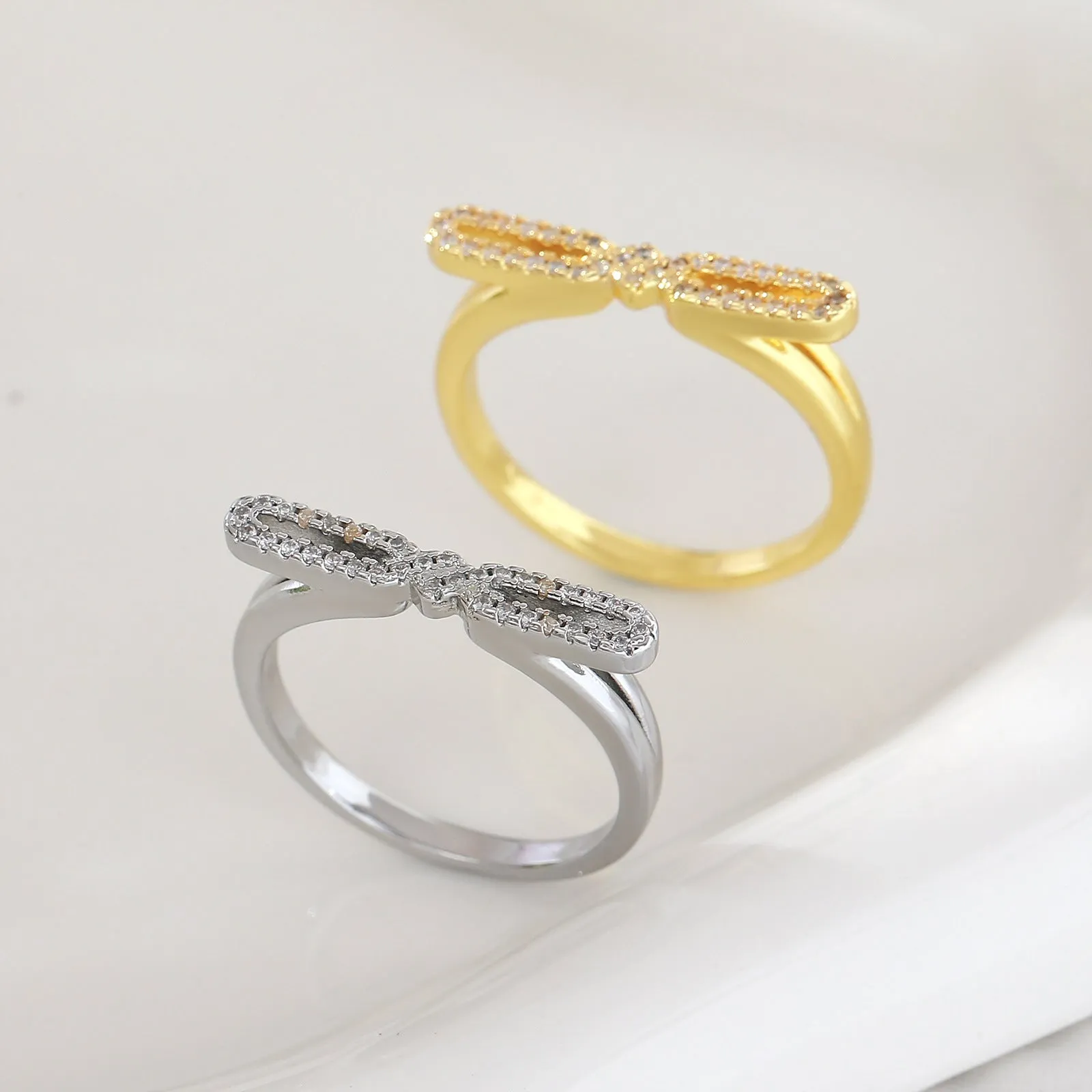 Fashion bowknot ring for women, copper with electroplated gold finish, bow shape on white background