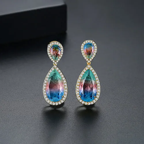 Drop shape copper earrings with inlaid synthetic gemstone in blue colour option on a white background