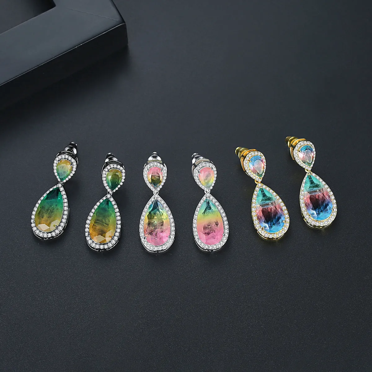 Drop shape copper earrings with inlaid synthetic gemstone in blue colour option on a white background