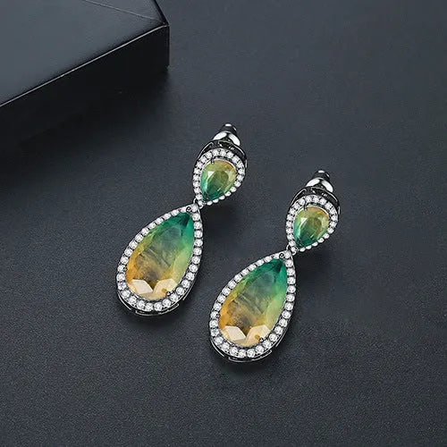 Drop shape copper earrings with inlaid synthetic gemstone in blue colour option on a white background