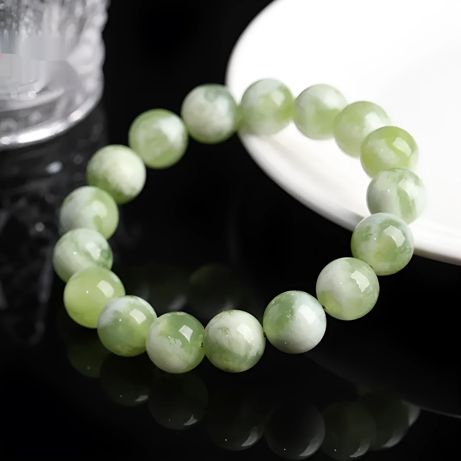 Green milk-in-water Xiuyan jade bracelet with geometric beads on white background