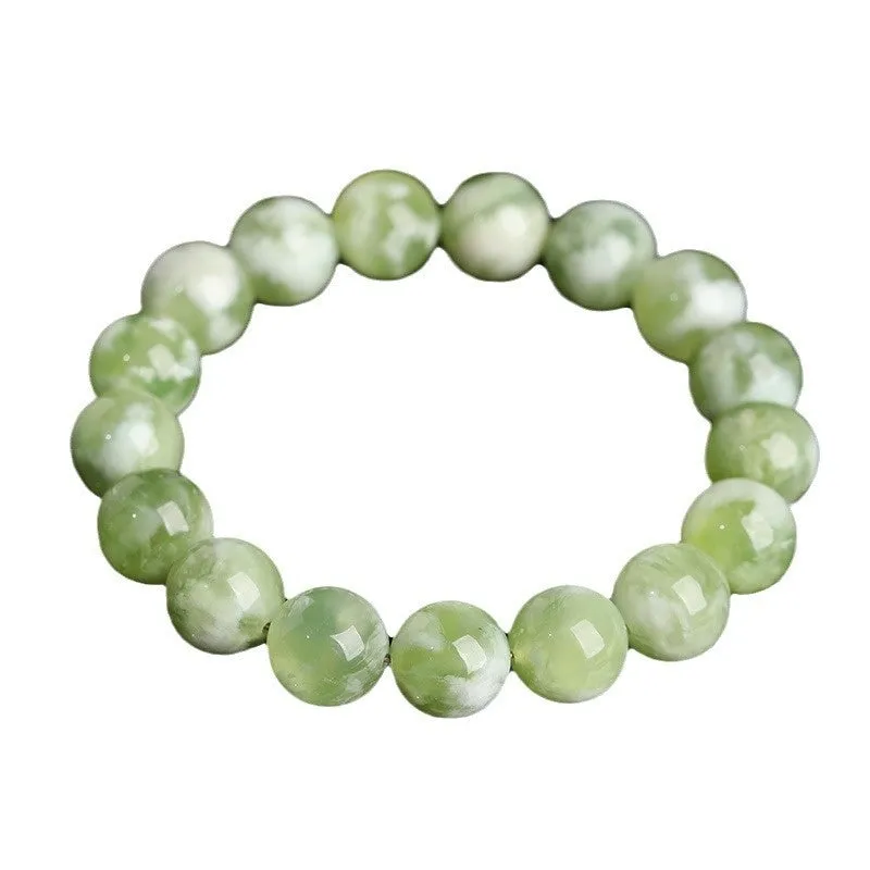 Green milk-in-water Xiuyan jade bracelet with geometric beads on white background