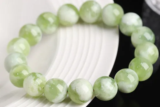 Green milk-in-water Xiuyan jade bracelet with geometric beads on white background