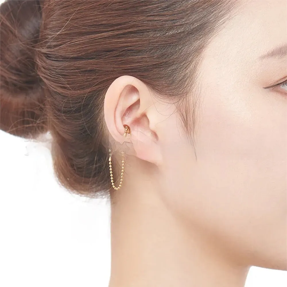 Ball chain tassel ear clip in gold on left ear, copper geometric U-shaped design