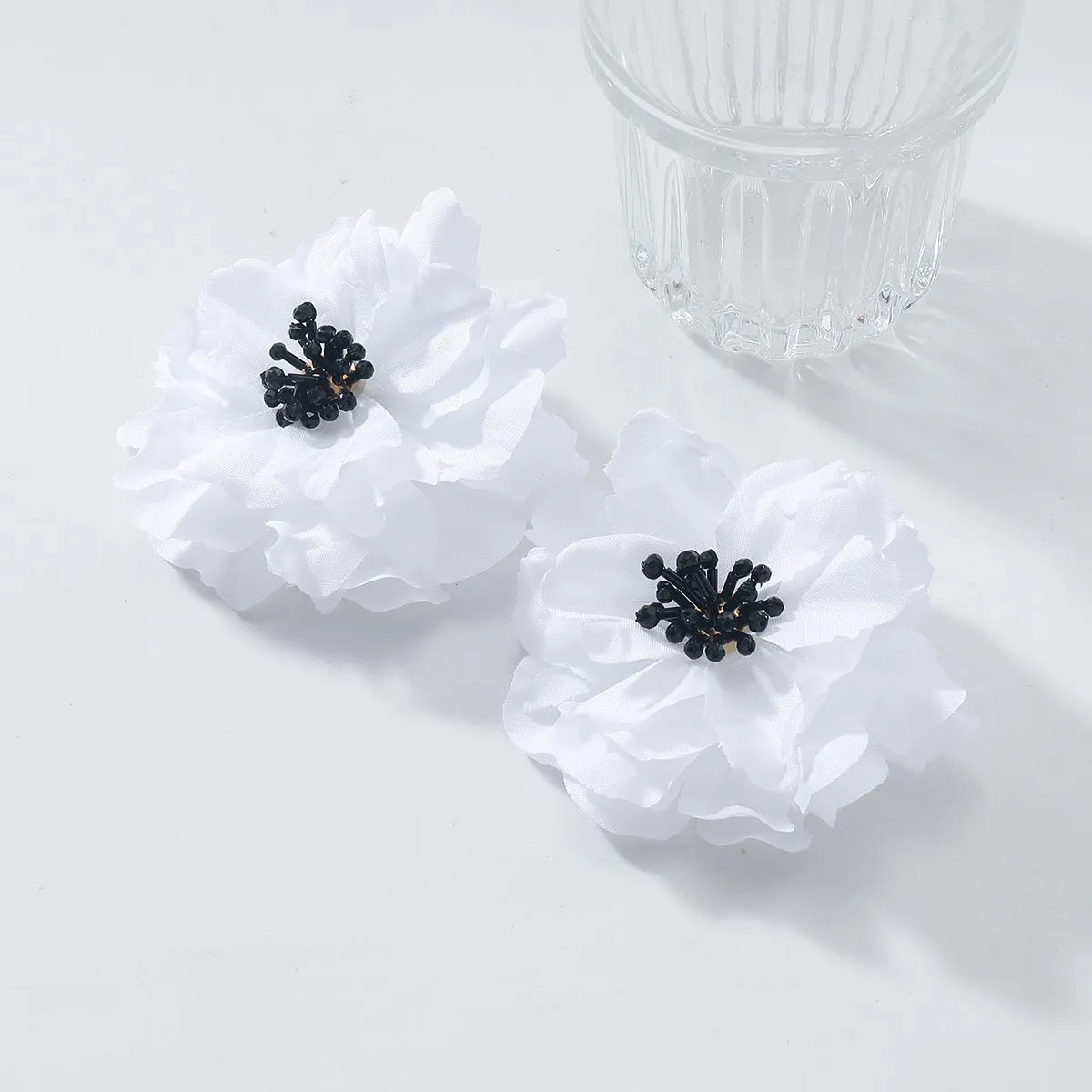 Hand-woven white plastic resin flower earrings for women fashion OL style on display