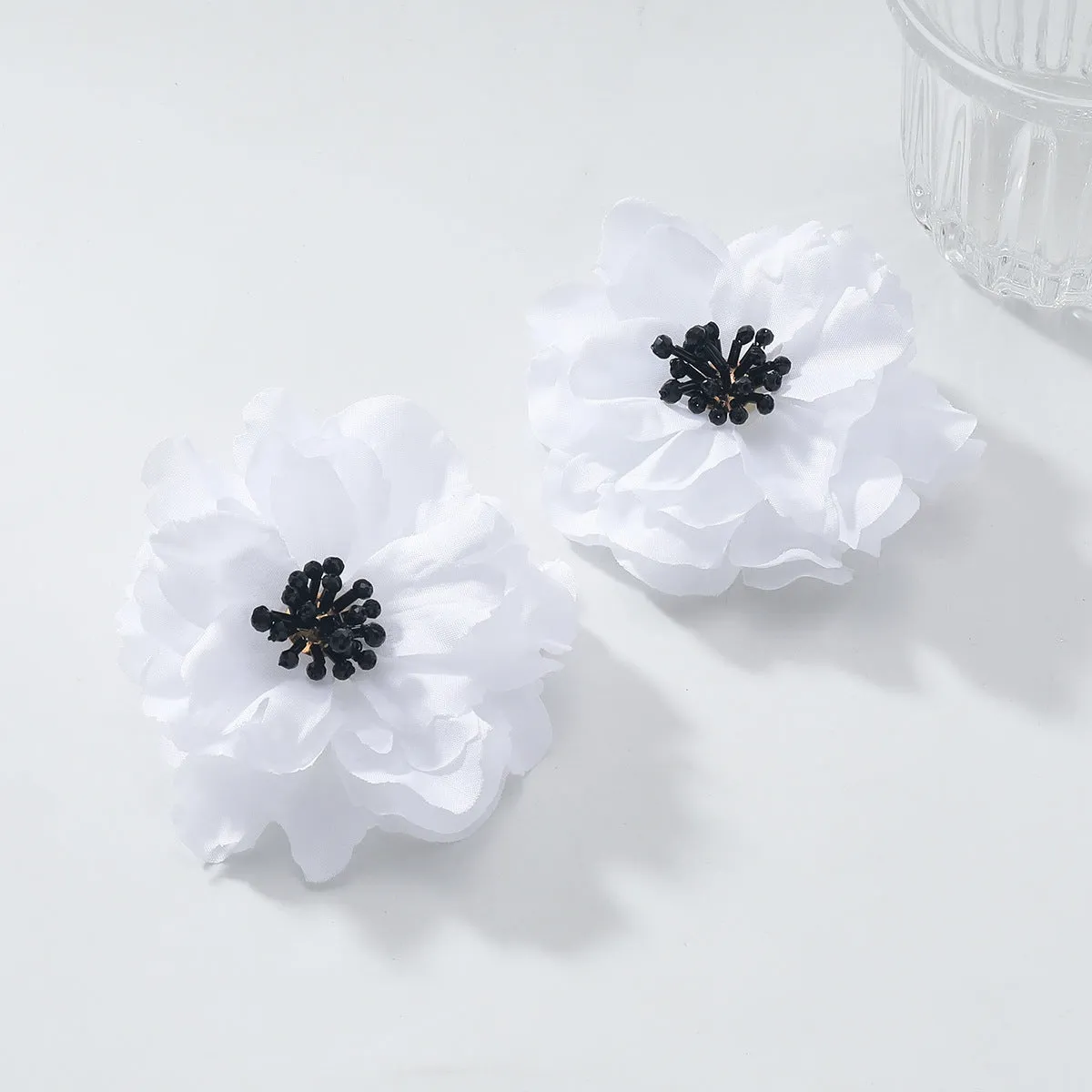 Hand-woven white plastic resin flower earrings for women fashion OL style on display