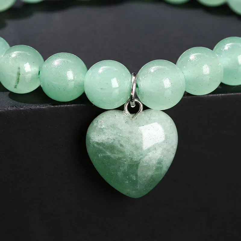 Natural stone love heart pendant bracelet on wrist, showing Tigereye, crystal or aventurine beads.