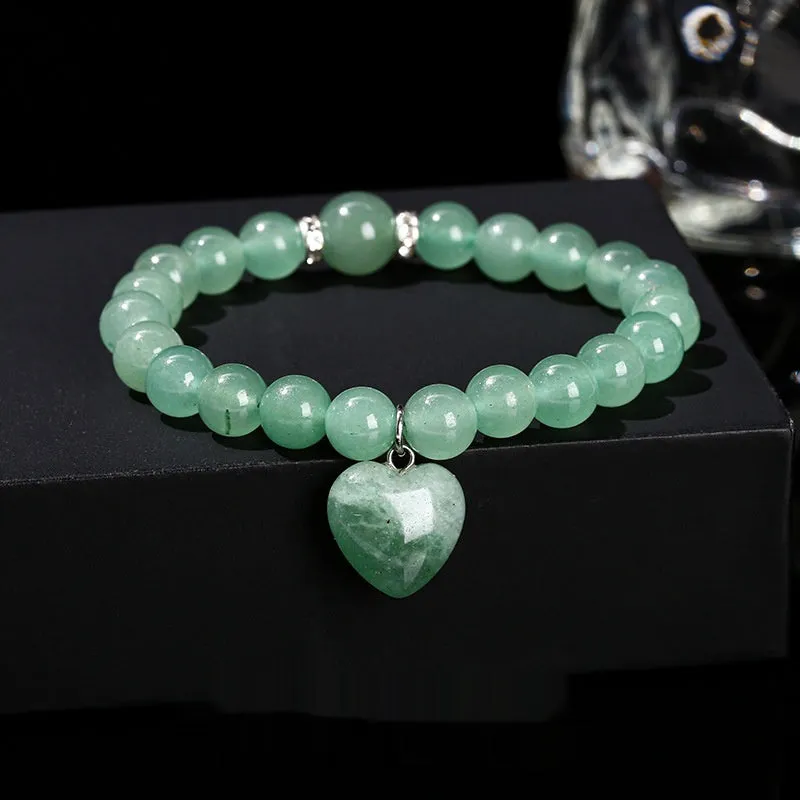 Natural stone love heart pendant bracelet on wrist, showing Tigereye, crystal or aventurine beads.