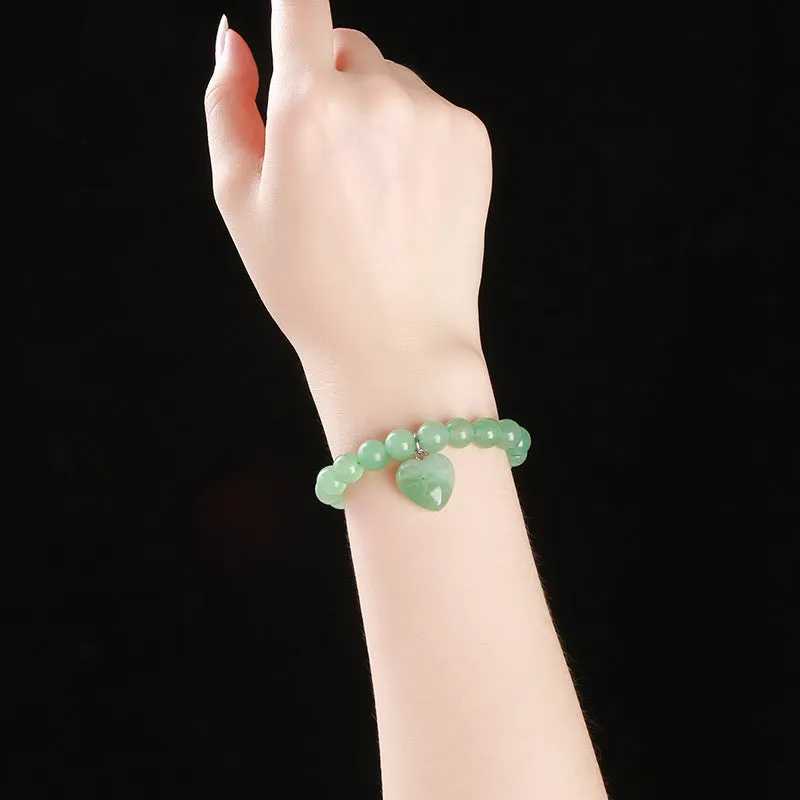 Natural stone love heart pendant bracelet on wrist, showing Tigereye, crystal or aventurine beads.