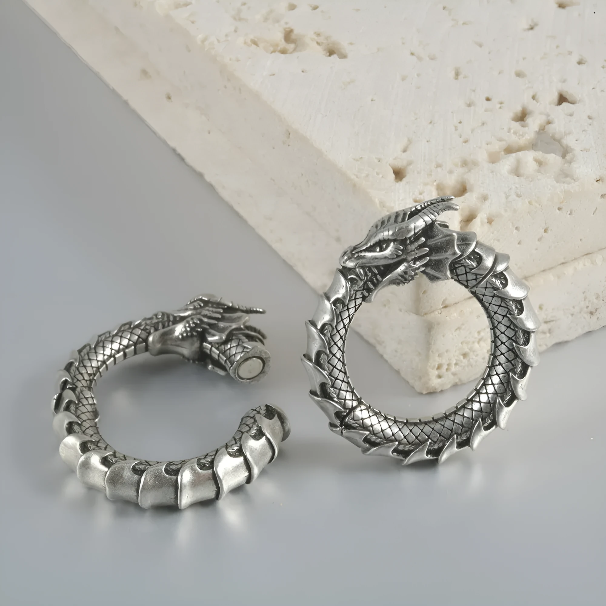 Large antique silver dragon-shaped hollow out copper auricle earrings on a white background.