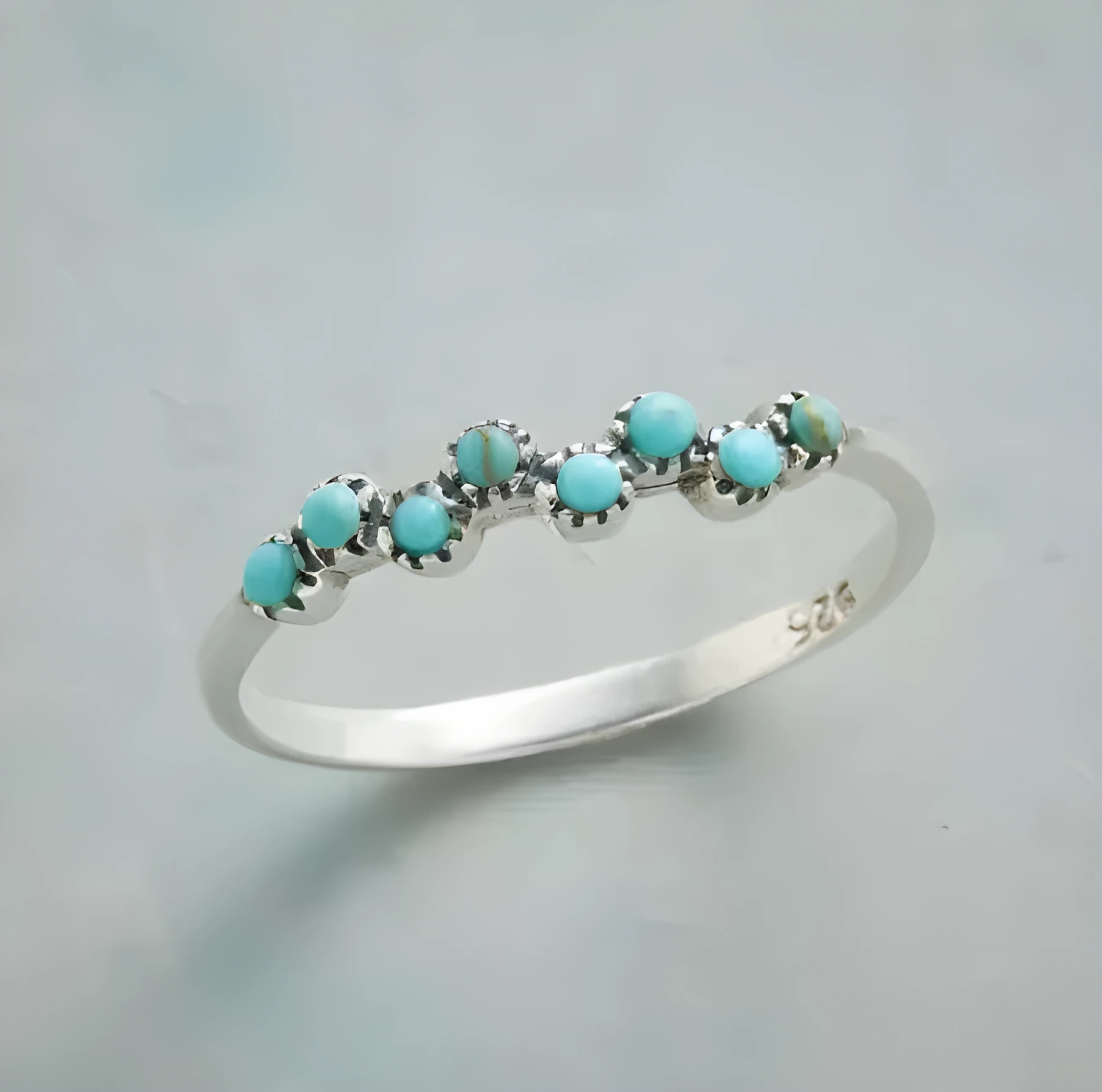 Silver bubble ring with eight-leaf green agate stone on a plain background