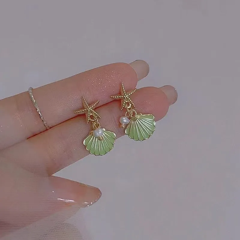 14K gold starfish shell earrings in light green on a white background