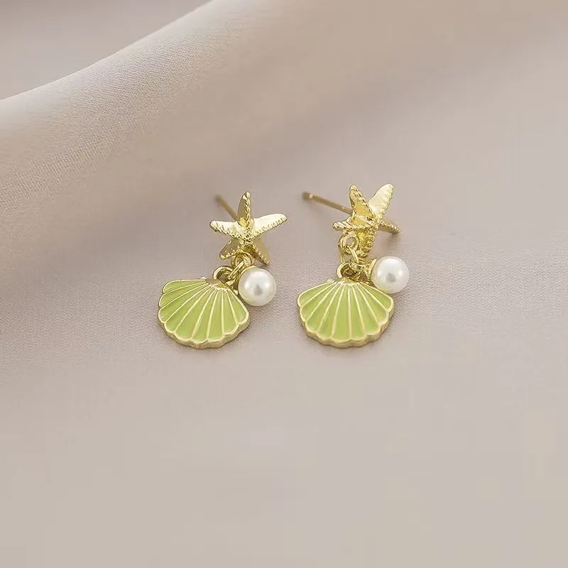 14K gold starfish shell earrings in light green on a white background