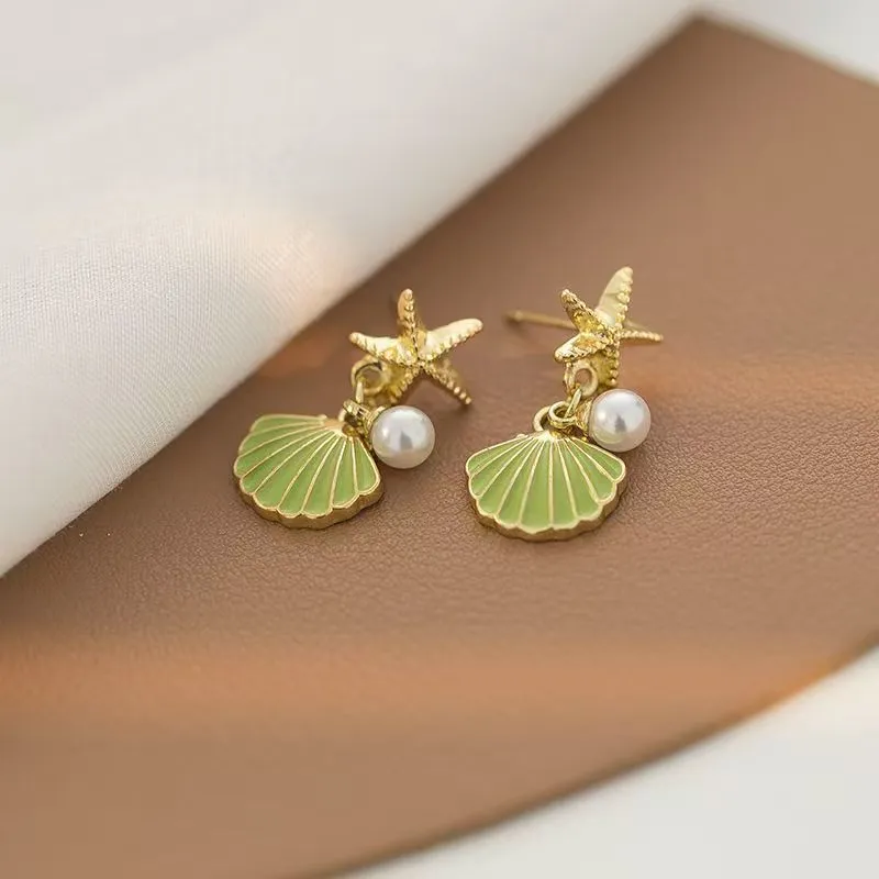 14K gold starfish shell earrings in light green on a white background