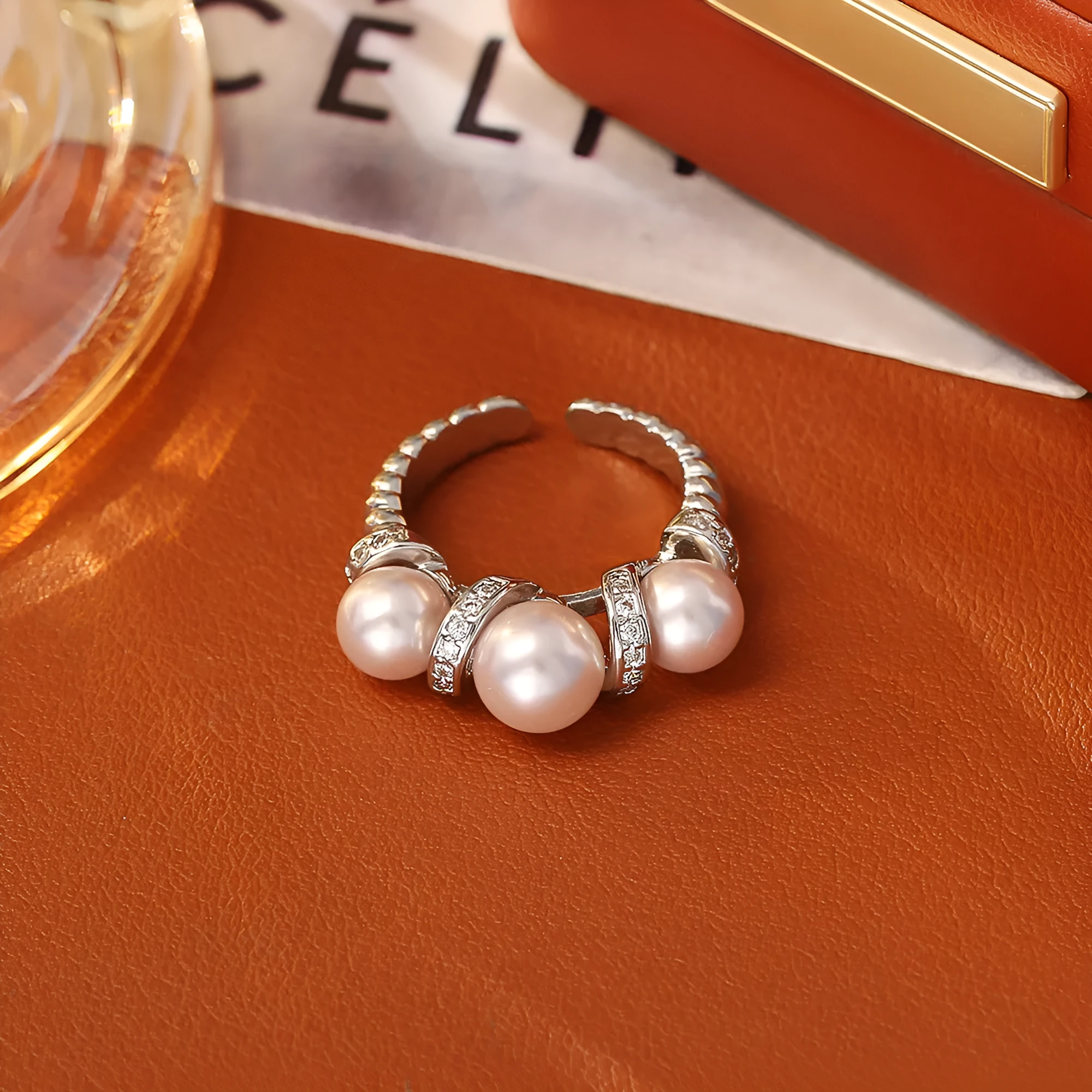 Real gold plated copper open-end ring with round pearl in geometric setting, grey colour, on a neutral background