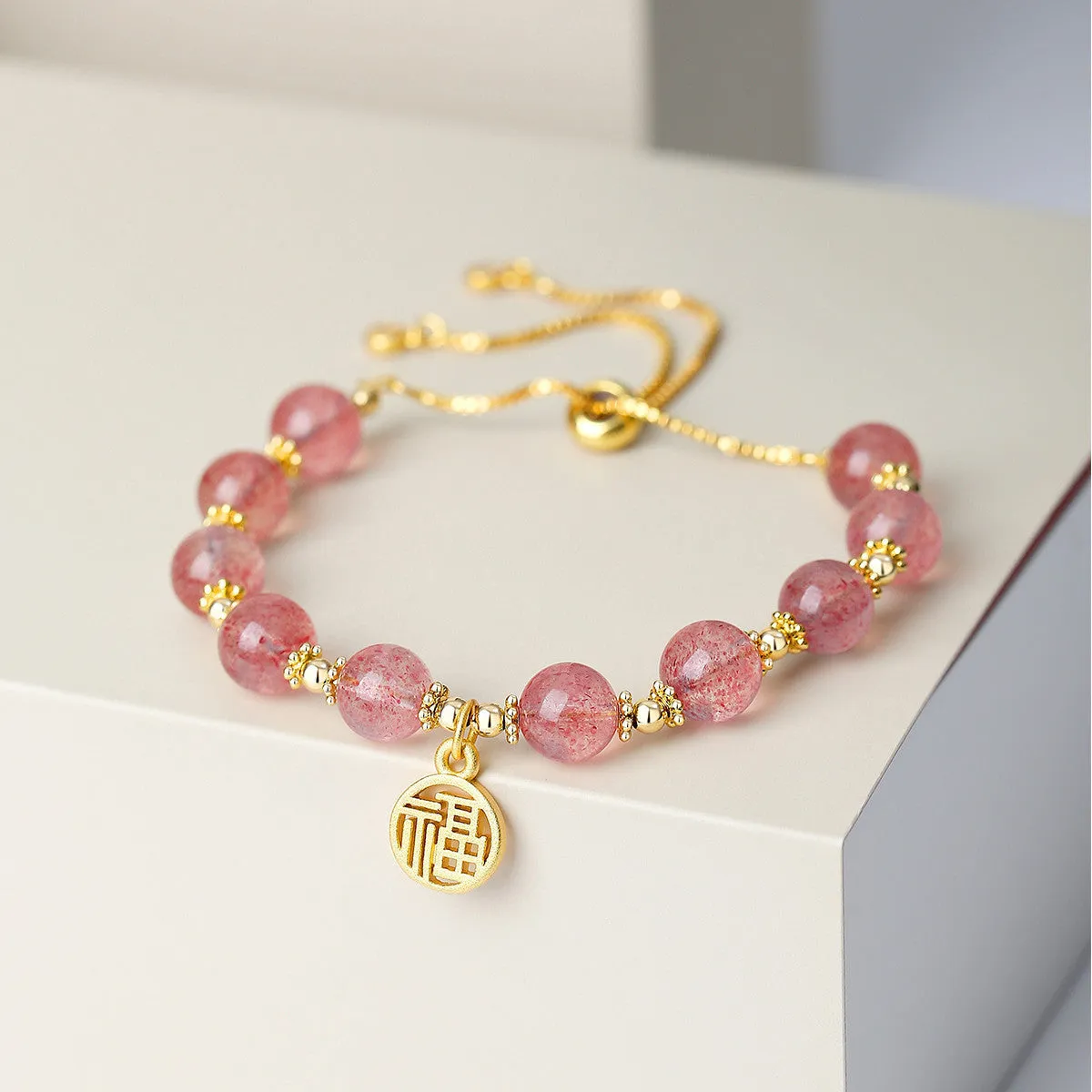 Women's strawberry quartz crystal bracelet with electroplated fu character charm and geometric design