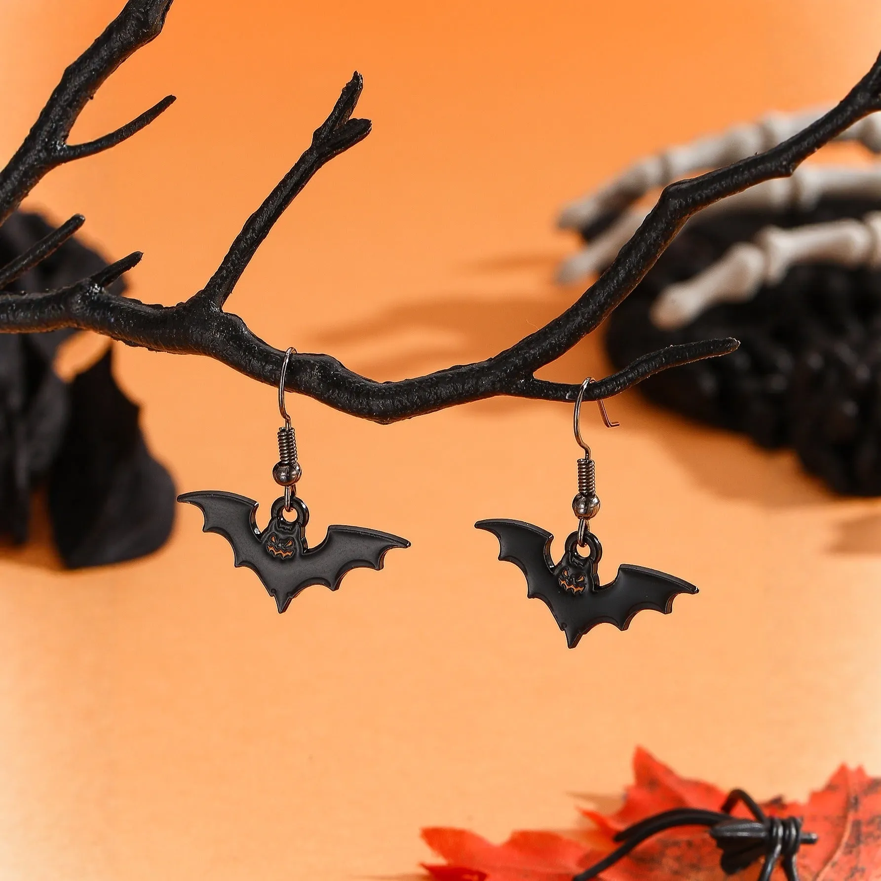 Set of six Halloween earrings with bat, cat, pumpkin head, skeleton, spider, and witch motifs on a dark background