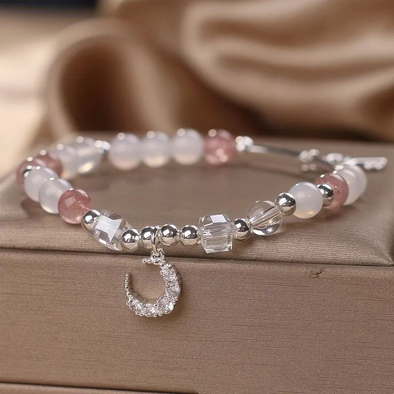 Natural strawberry quartz bracelet with pink cube sugar beads and moon pendant on a flat surface