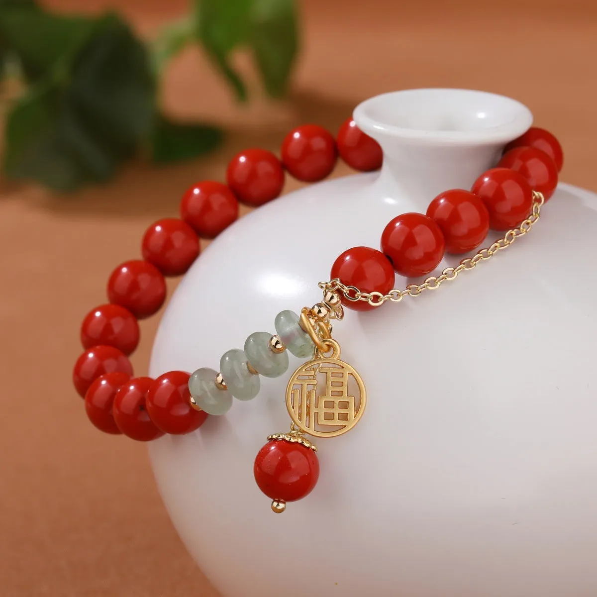 Women's red cinnabar bracelet with fu character charm, jade spacer bead, and tassel design