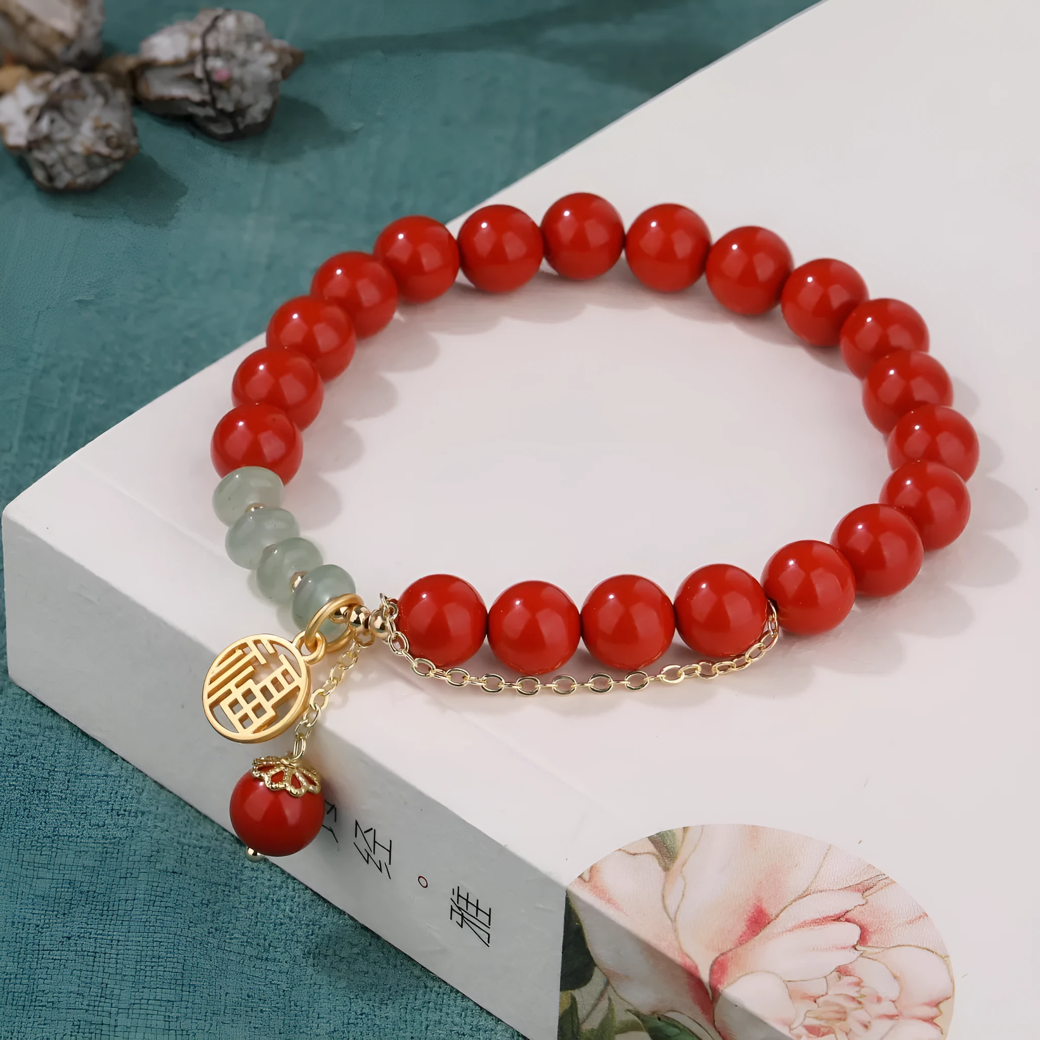 Women's red cinnabar bracelet with fu character charm, jade spacer bead, and tassel design