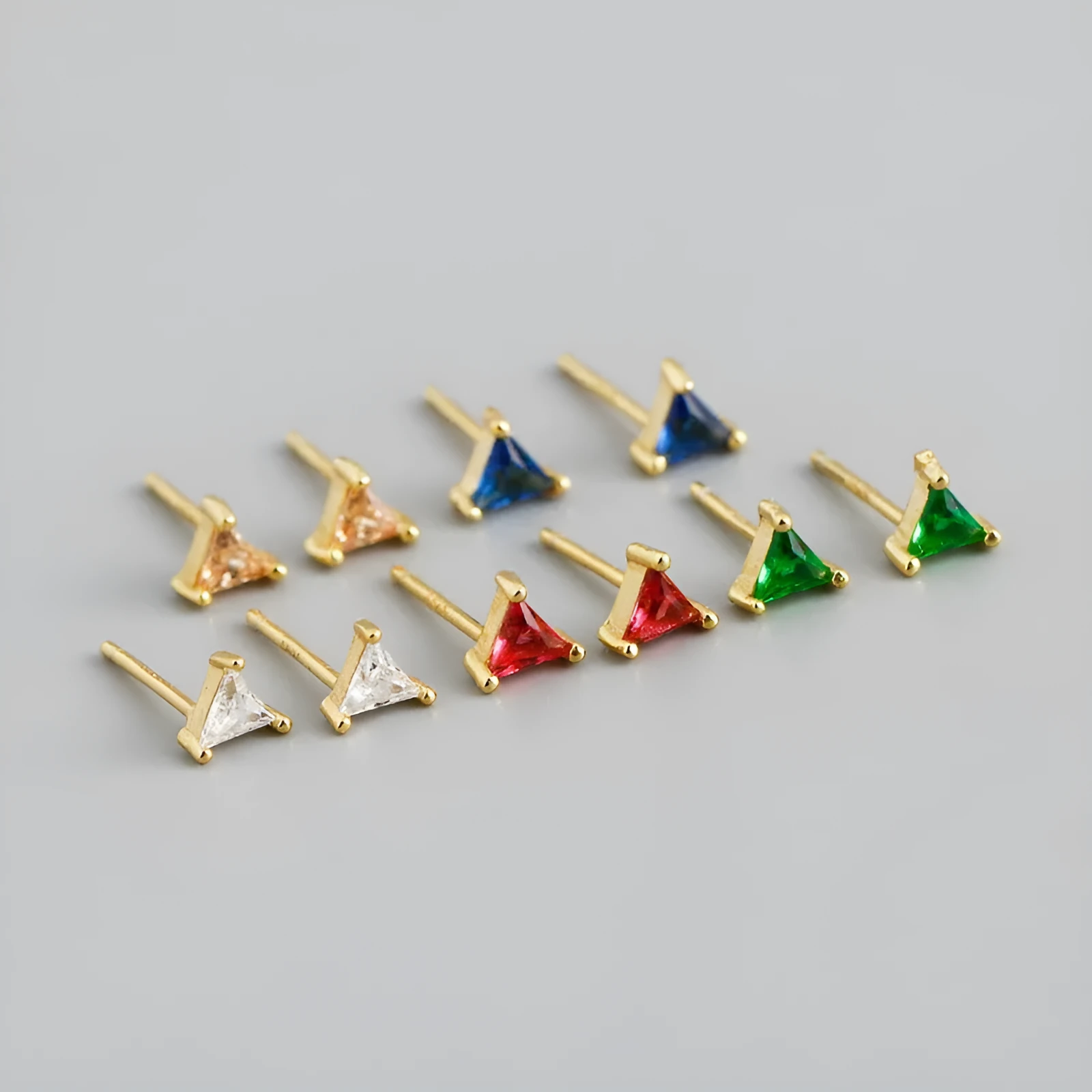 Simple triangle colour zircon stud earrings in 925 sterling silver with blue stone and gold needle on white background