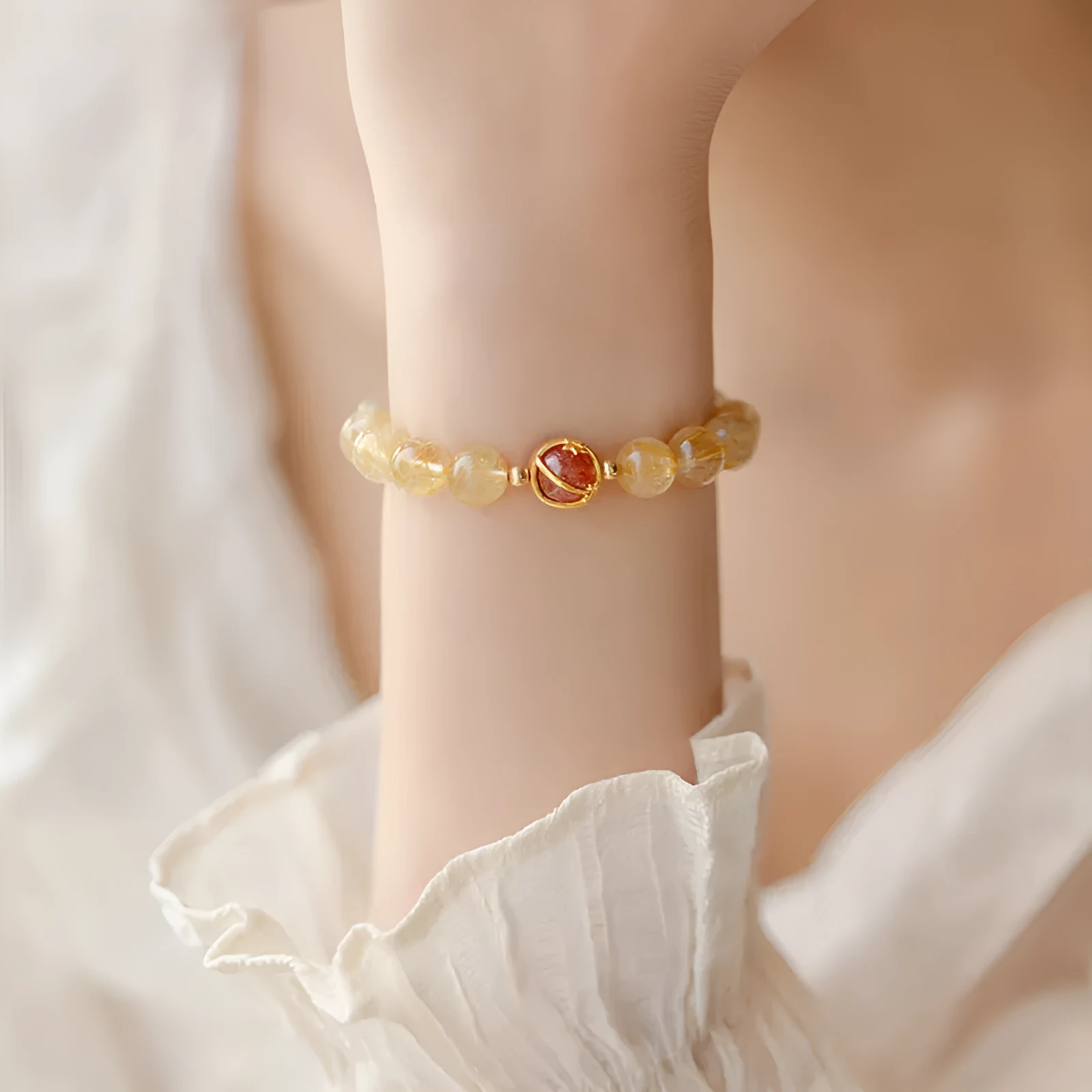 Citrine and gold rutilated quartz bracelet with diamond-cut beads in 6mm or 8mm size on a wrist.