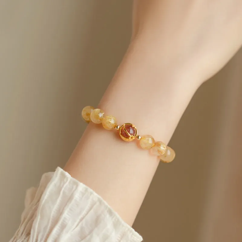 Citrine and gold rutilated quartz bracelet with diamond-cut beads in 6mm or 8mm size on a wrist.