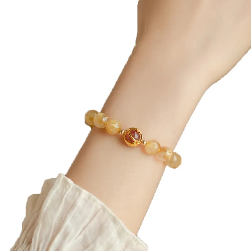 Citrine and gold rutilated quartz bracelet with diamond-cut beads in 6mm or 8mm size on a wrist.