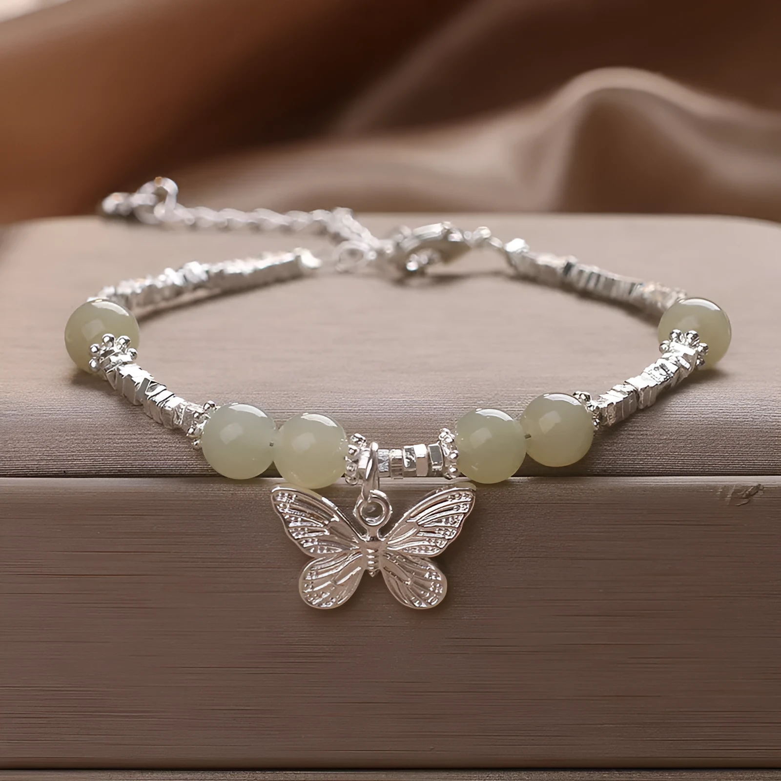 Hetian jade beads bracelet with silver butterfly pendant on a white background