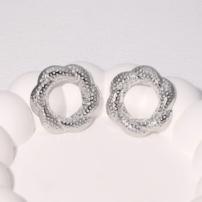 Stainless steel round stud earrings in gold and steel colours on a neutral background