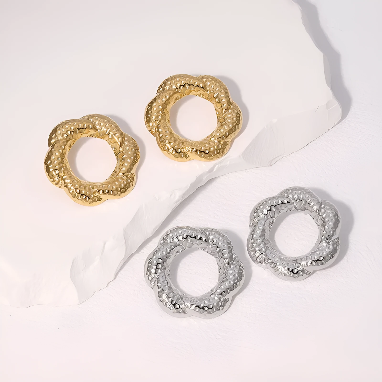 Stainless steel round stud earrings in gold and steel colours on a neutral background