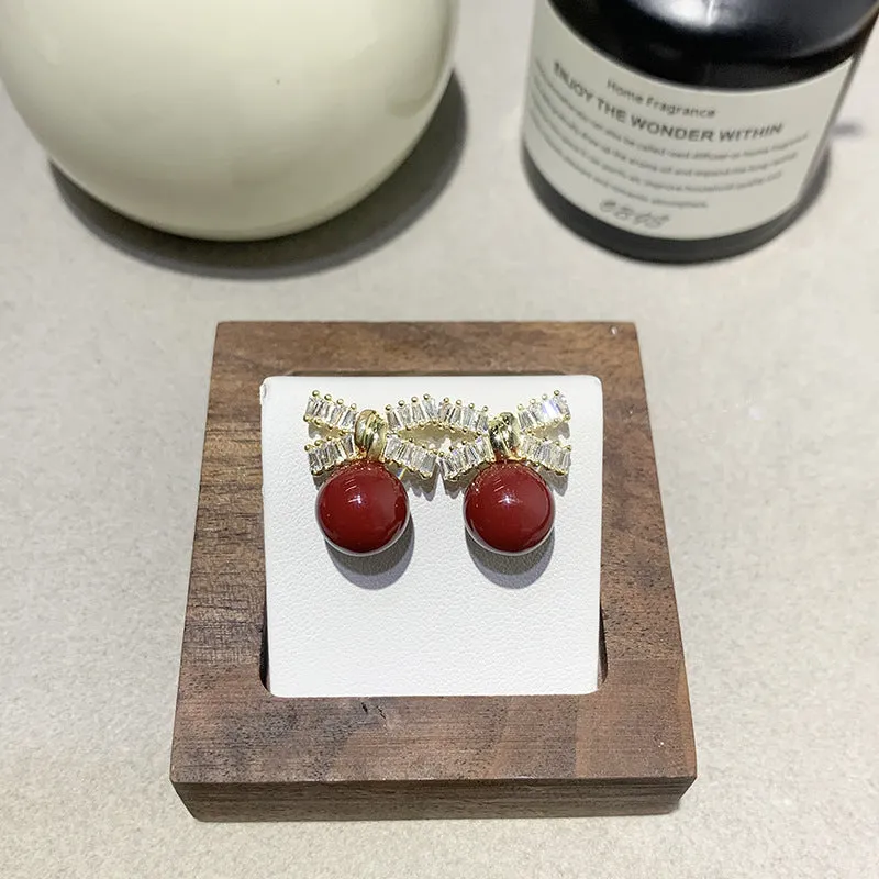 Silver needle micro inlaid zircon bow pearl drop earrings on a light background