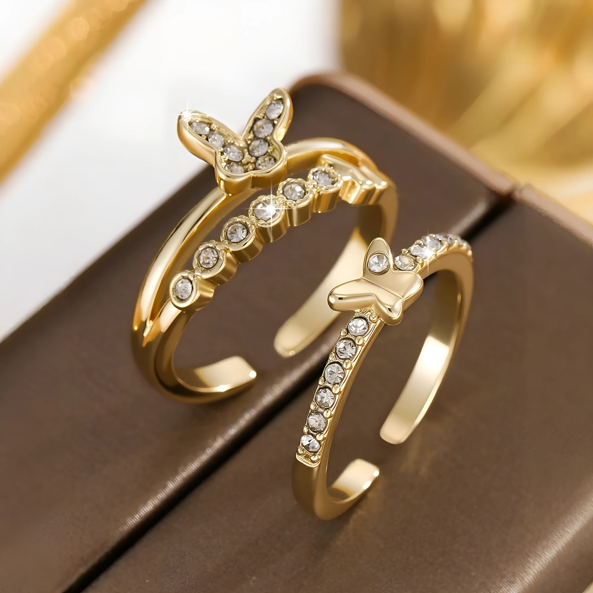 Gold adjustable butterfly ring on finger against white background