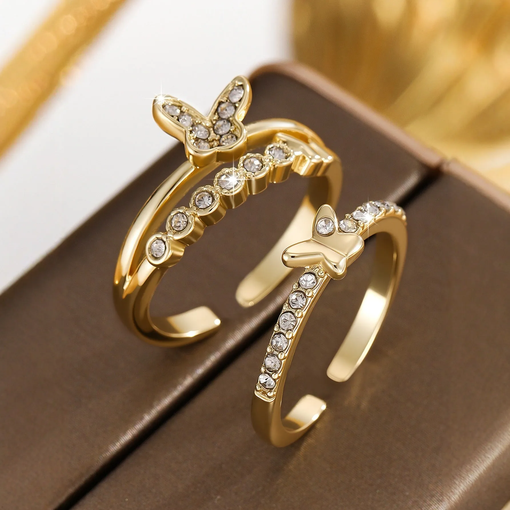 Gold adjustable butterfly ring on finger against white background