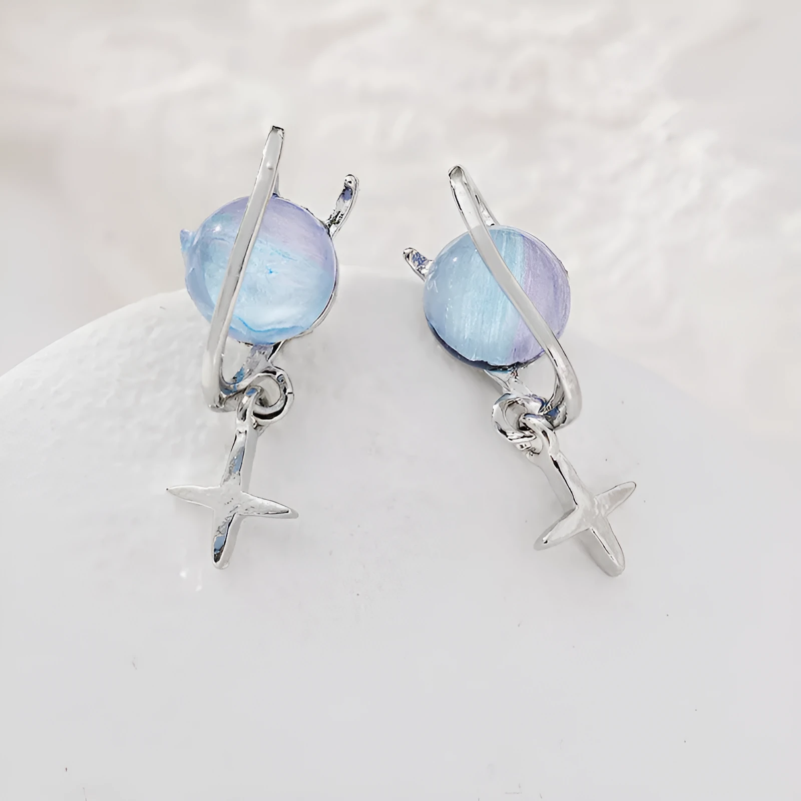 Metal geometric planet earrings in multicolour finish on a neutral background