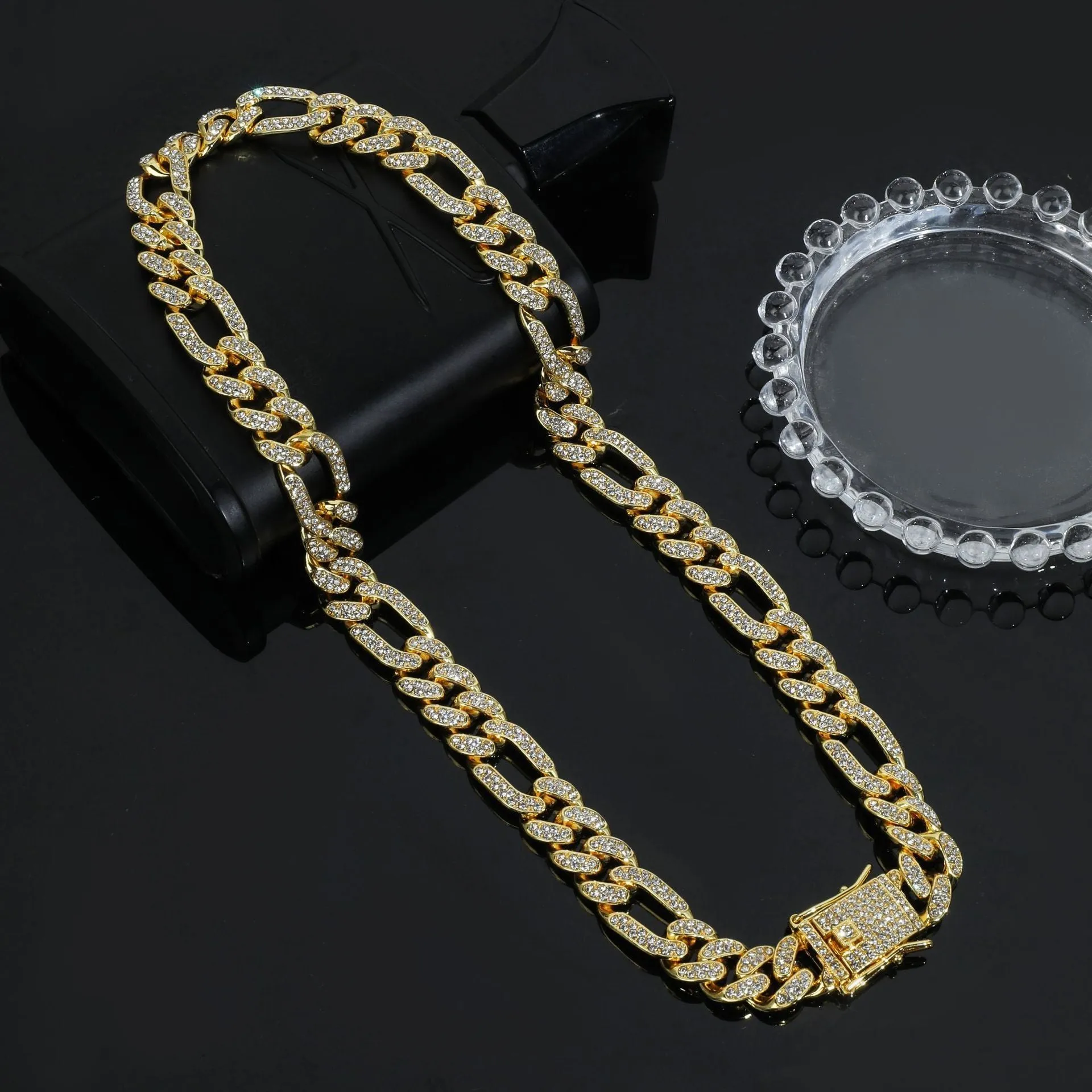 Rap style figaro chain necklace with geometric rhinestone pendant in silver colour on a plain background