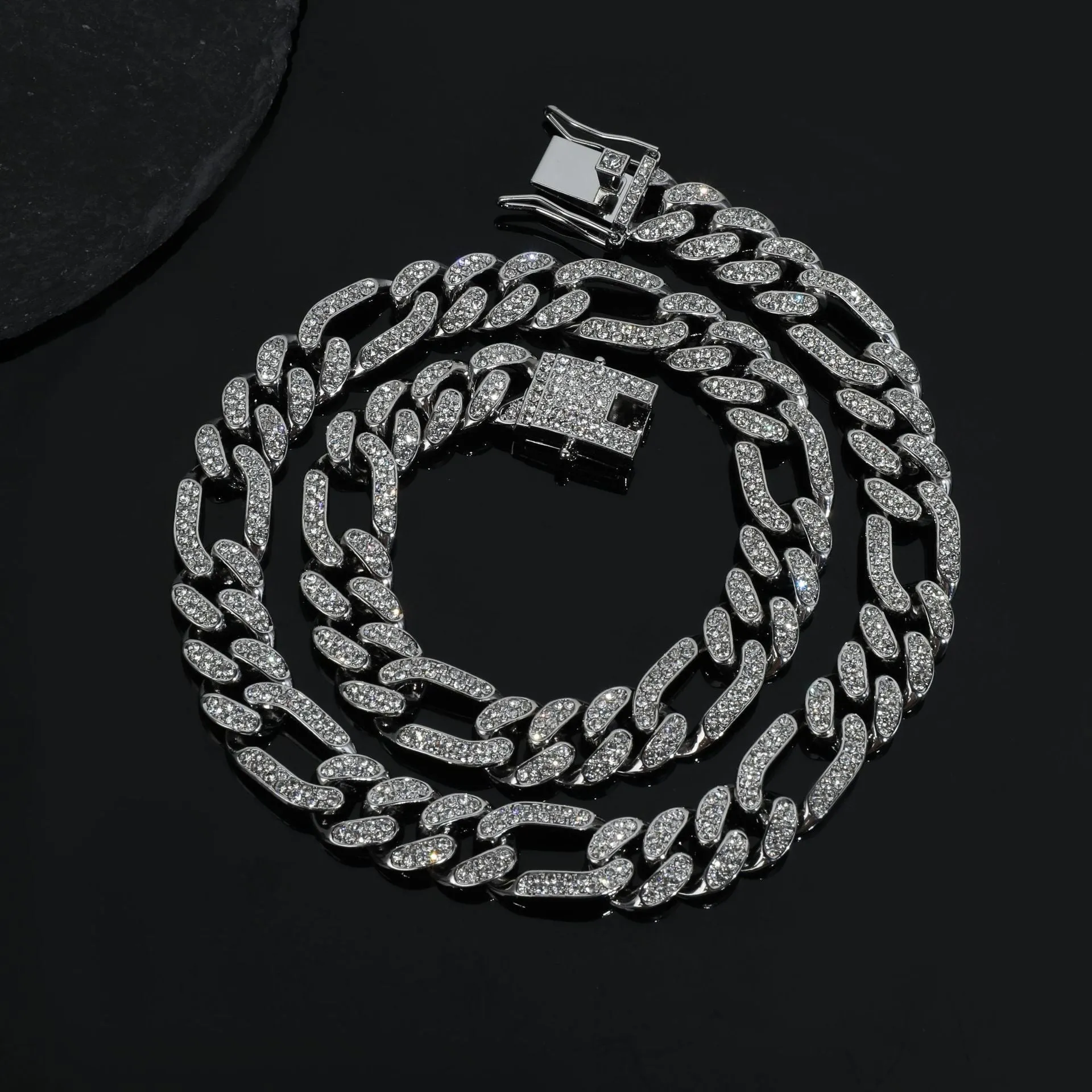 Rap style figaro chain necklace with geometric rhinestone pendant in silver colour on a plain background