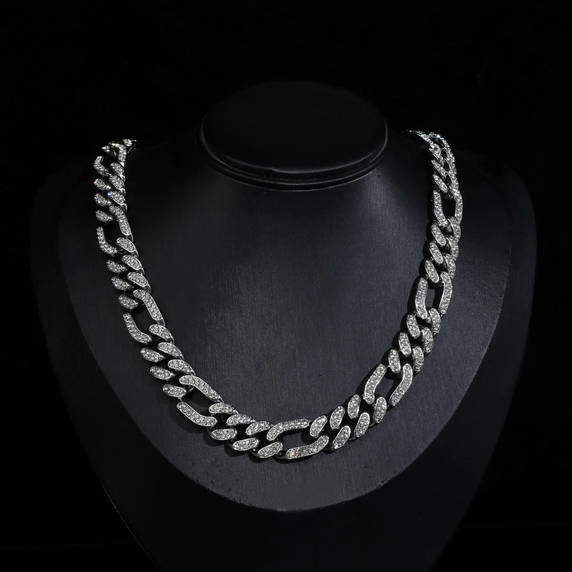 Rap style figaro chain necklace with geometric rhinestone pendant in silver colour on a plain background
