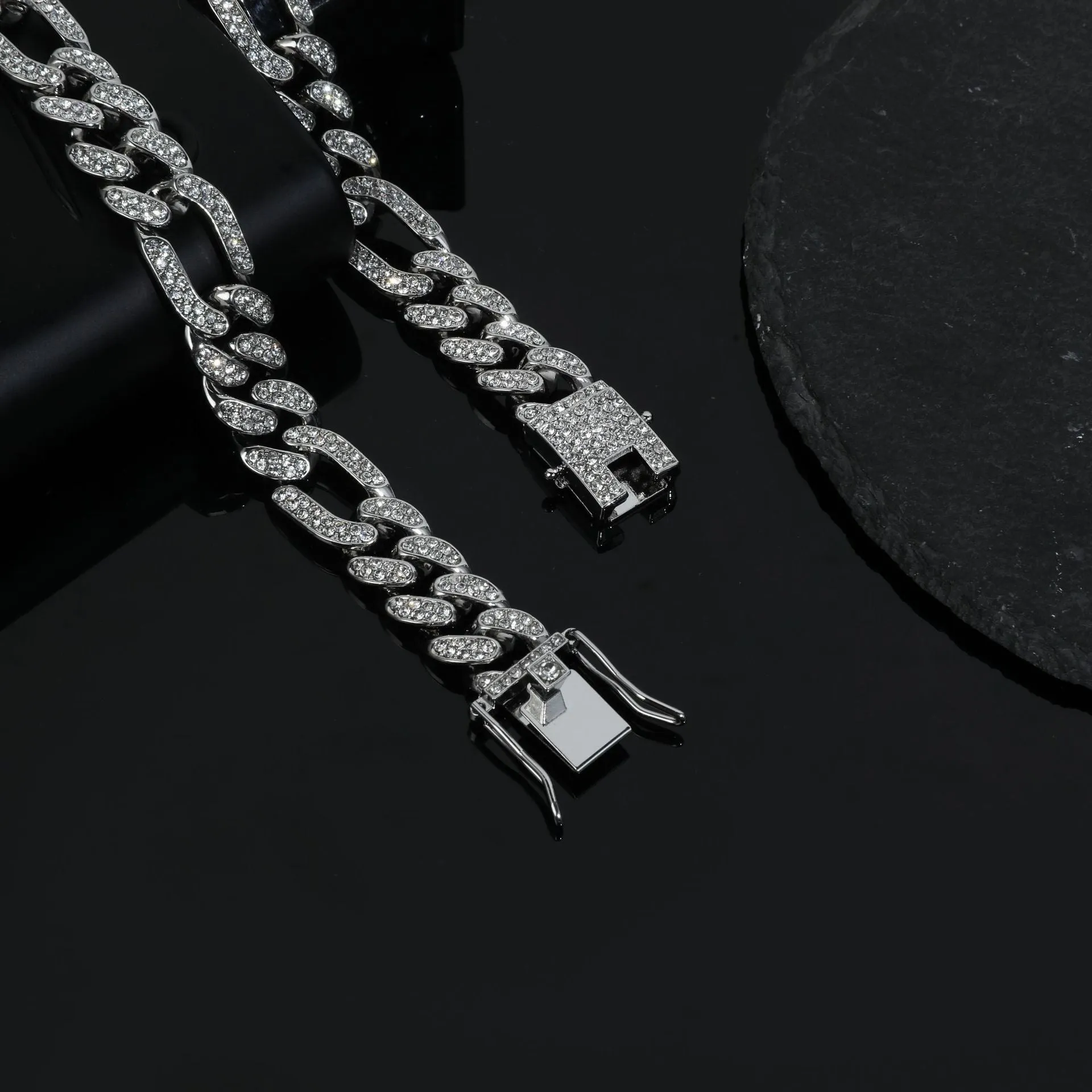 Rap style figaro chain necklace with geometric rhinestone pendant in silver colour on a plain background